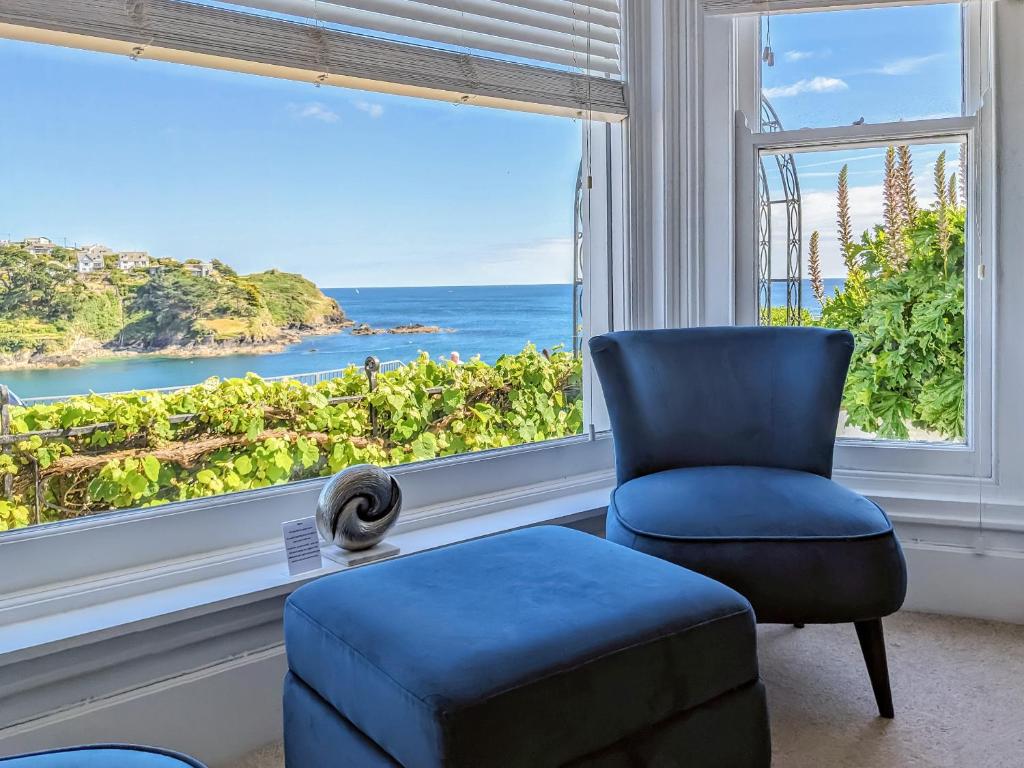 a blue chair and a stool in front of a window at Seascape - St Catherine's Court in Fowey