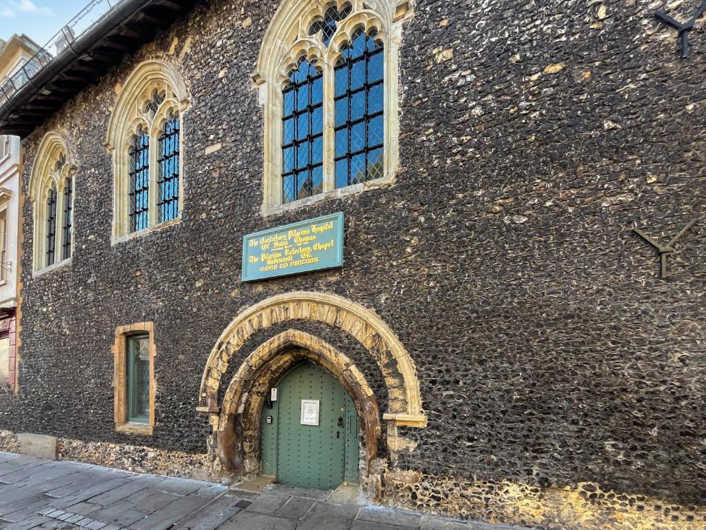 a large stone building with a green door and windows at The Friars Apartment, Eastbridge Hospital in Canterbury