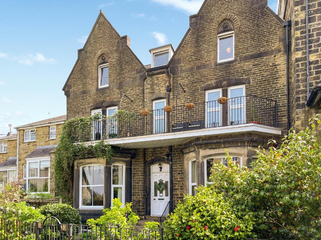 an old brick house with a balcony at Sefton House Apartment in Ilkley