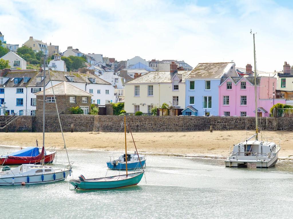 three boats in the water near a beach with houses at Blue Beach House in Ilfracombe