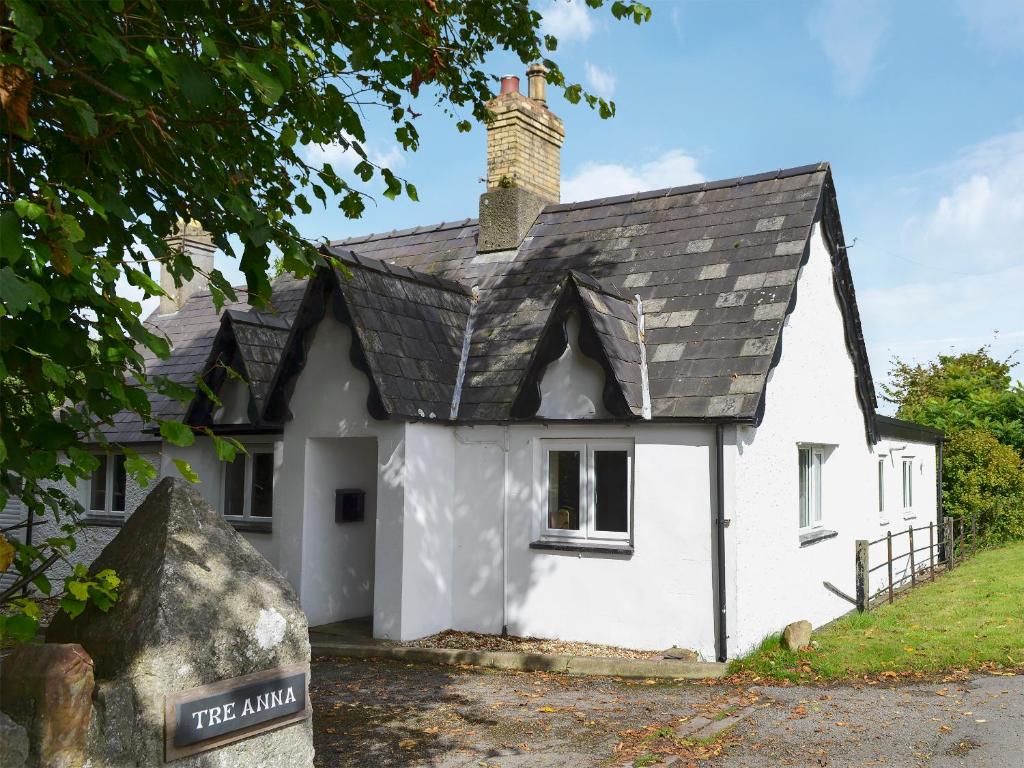 a small white house with a black roof at Tre Anna Lodge in Dwyran