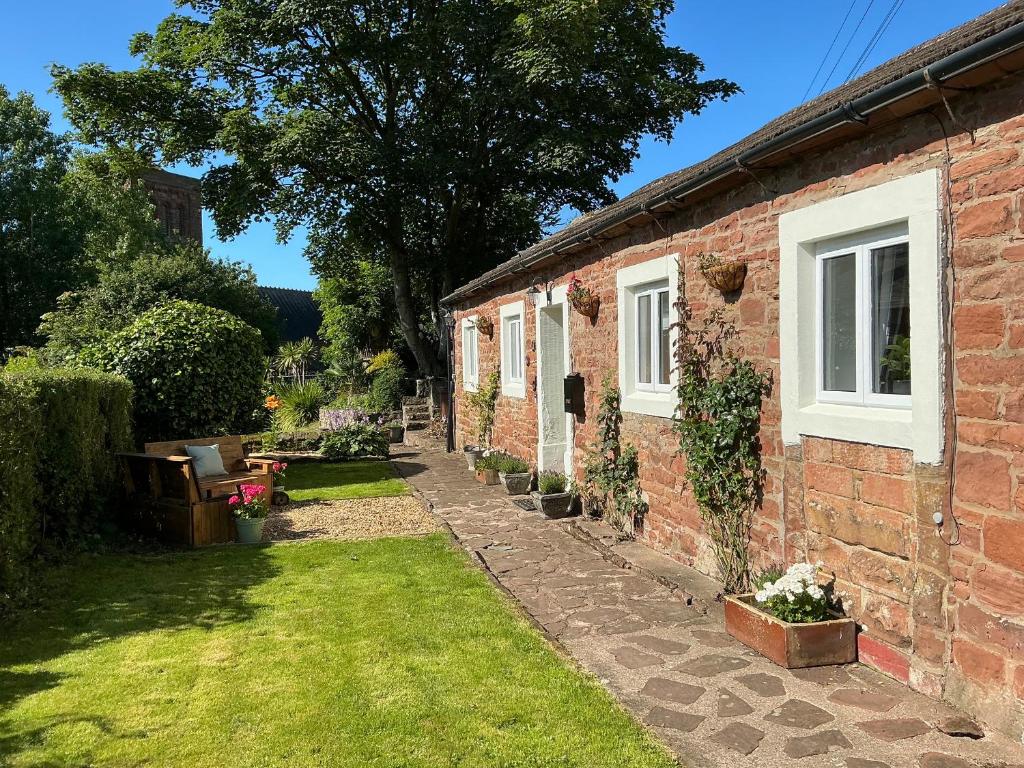 a brick house with a grass yard in front of it at Abbey Cottage in St Bees