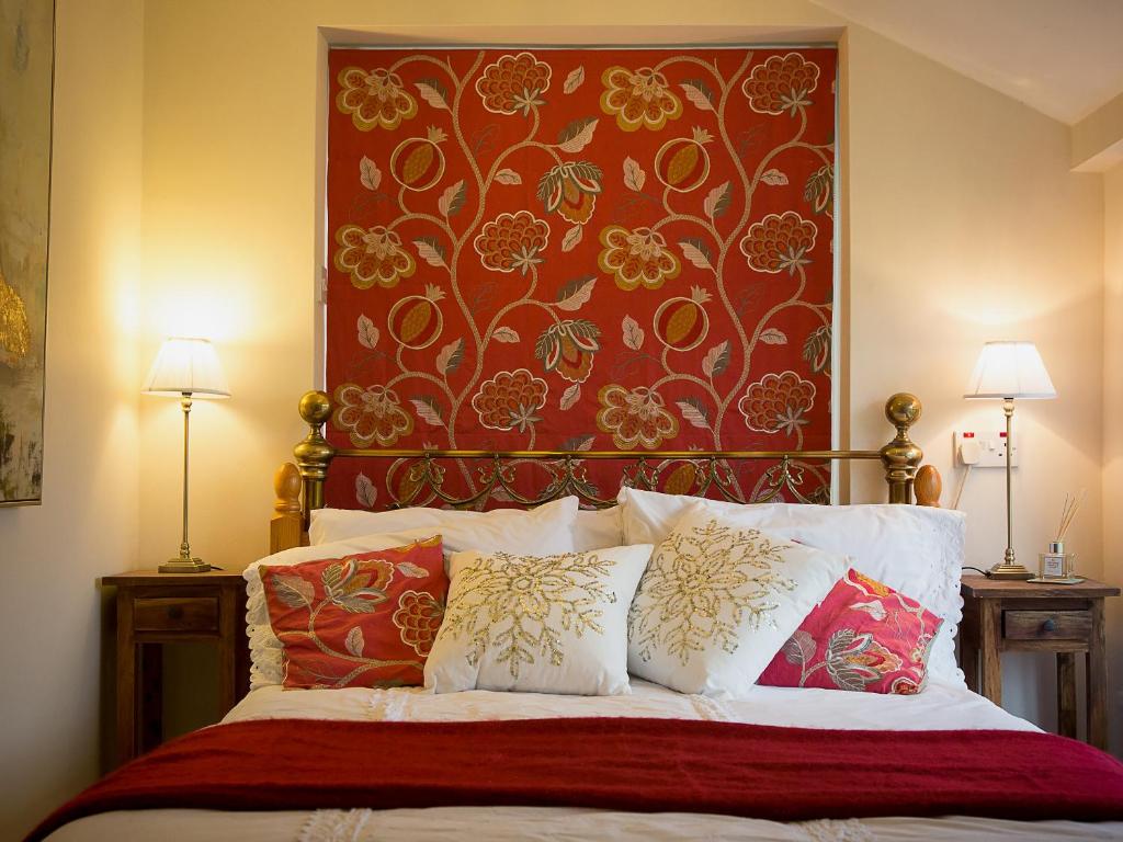 a bedroom with a bed with a red headboard and pillows at Gamekeeper's Cottage in Staple