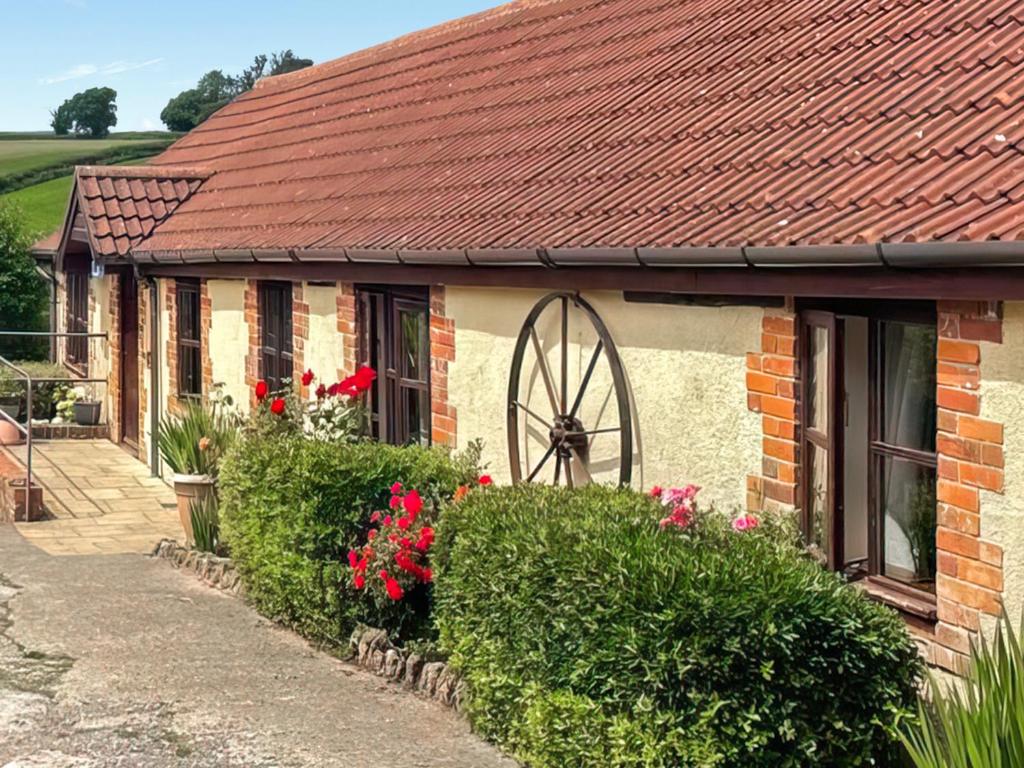 a brick house with a red roof and flowers at Parlour Cottage in Evershot