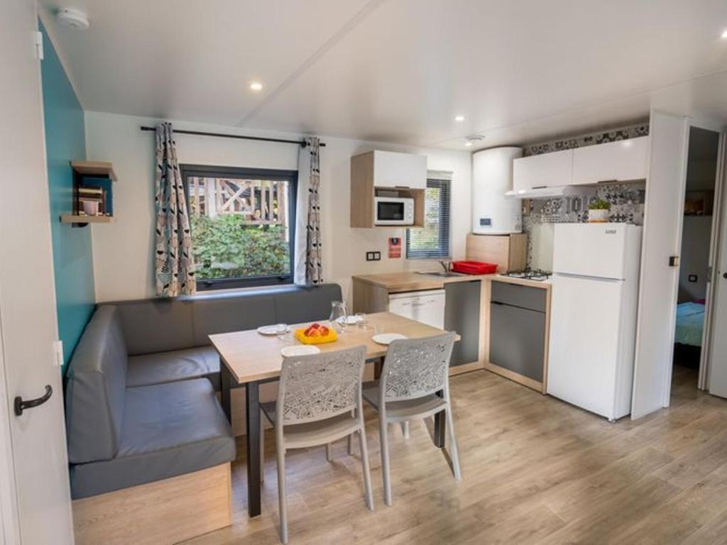 a kitchen and dining room with a table and a couch at Mobil home 32m² avec terrasse, 3 chambres pour 6 personnes - API-1-52-713 in Barbey-Séroux
