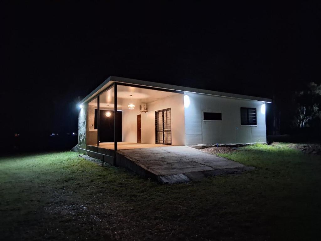 a small white building at night with lights at Chacra Lavanda Casas de Campo, 3 dormitorios in Salto