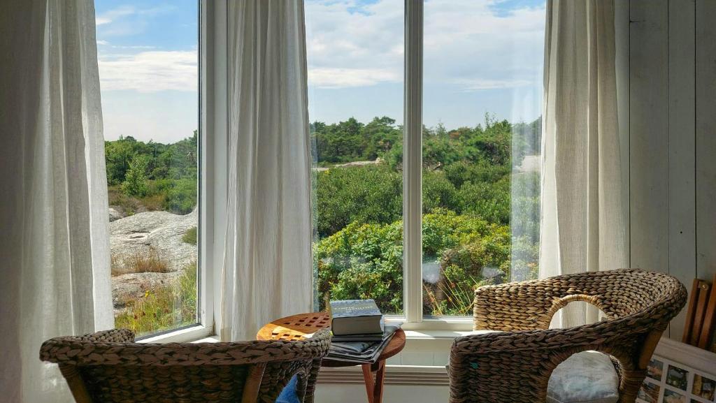 Una habitación con una gran ventana con dos sillas y una computadora portátil. en Holiday Home Overlooking Fishing Harbour In Hvaler, en Spjær