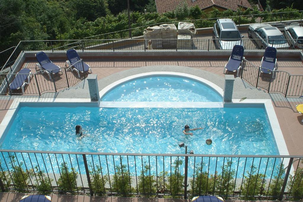 een zwembad waar drie mensen in zwemmen bij Residence Il Vigneto in Oggebbio