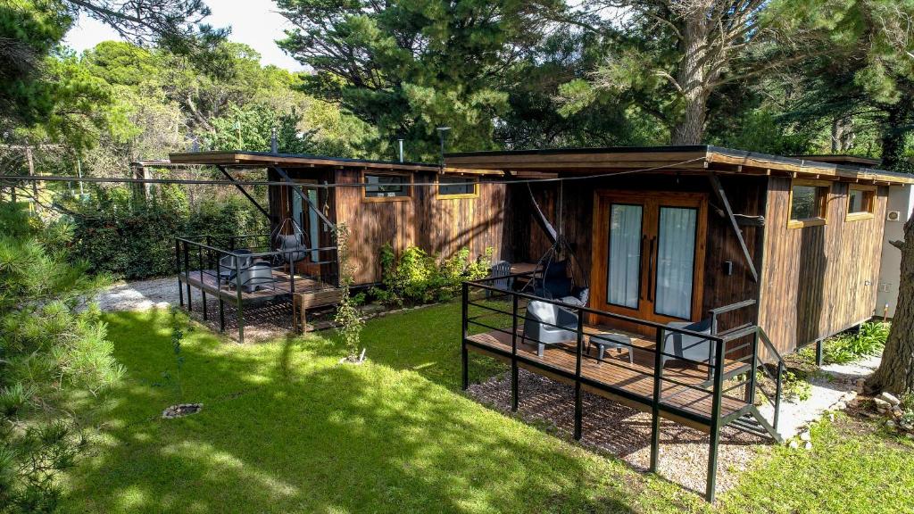 a small cabin with a porch in a garden at Arauca Lodge in Villa Ventana
