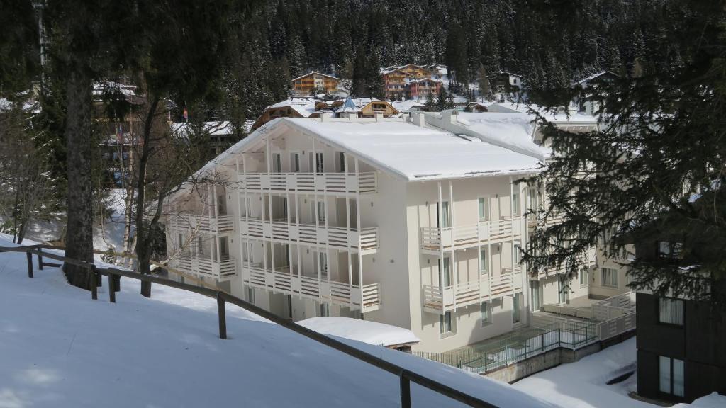 a large white building in the snow with trees at Residence Antares in Madonna di Campiglio
