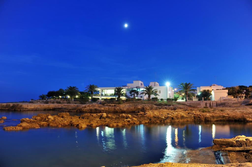 una vista di una città di notte con la luna di Hotel Il Timone a Specchiolla