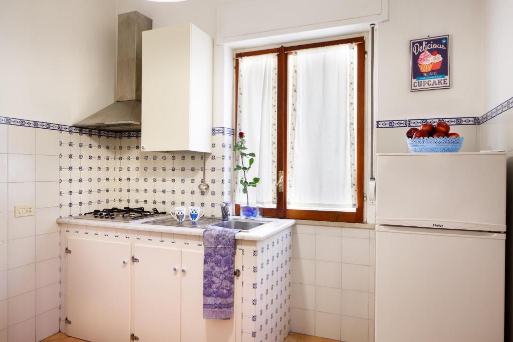 een keuken met witte kasten, een wastafel en een raam bij Casa Nonna Netta in Sorrento