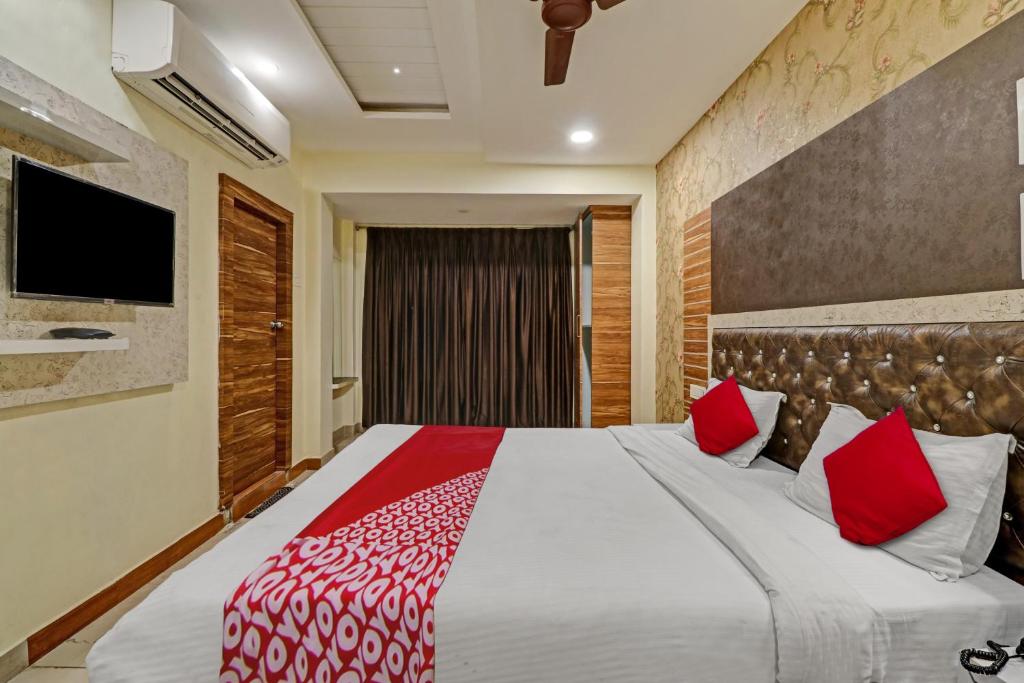 Hotel O Aditya Grand Inn في جونتور: غرفة نوم بسرير كبير مع وسائد حمراء