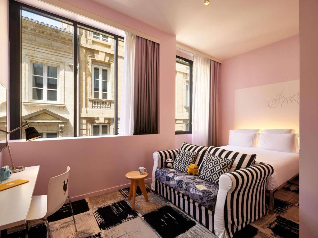 a hotel room with a couch and a bed and a window at Mama Shelter Bordeaux Centre in Bordeaux