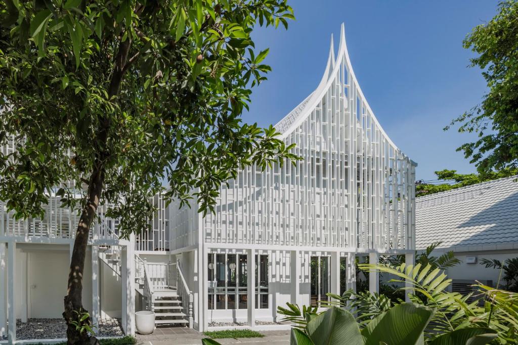 eine Außenansicht eines weißen Gebäudes mit einem Baum in der Unterkunft Busaba Ayutthaya Hotel in Phra Nakhon Si Ayutthaya