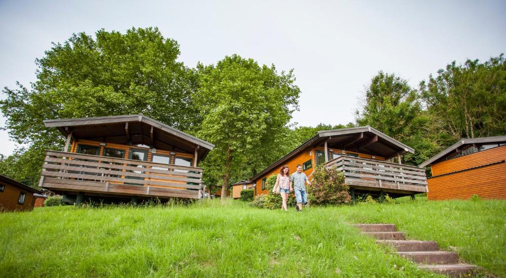 dos personas caminando delante de dos cabañas en Vallée Les Etoiles en Blaimont