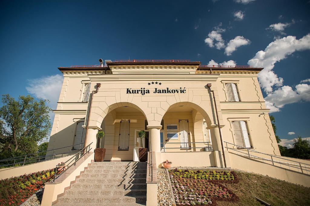 ein weißes Gebäude mit einer Treppe, die zum Eingang führt in der Unterkunft Hotel Kurija Janković in Lukač