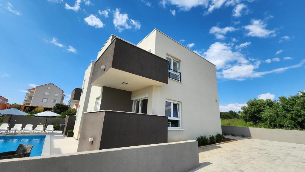 a white house with a swimming pool at The Sands LUXE Pool Aparthotel, Studio in Novalja
