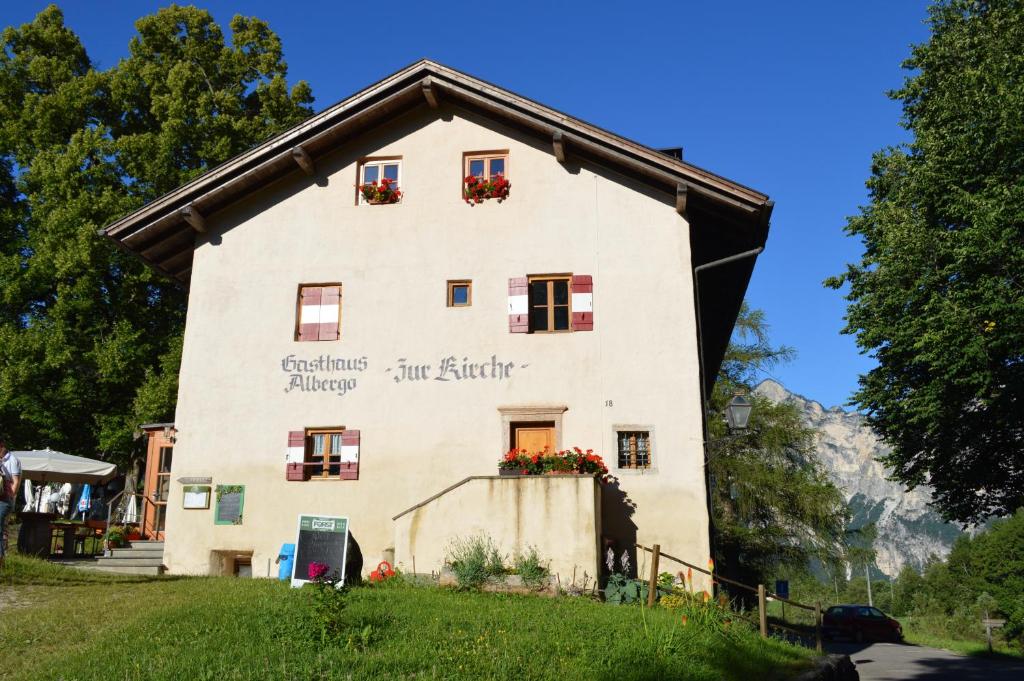 ein Haus in den Bergen mit Blumen in den Fenstern in der Unterkunft Hotel Zur Kirche in Margreid an der Weinstraße