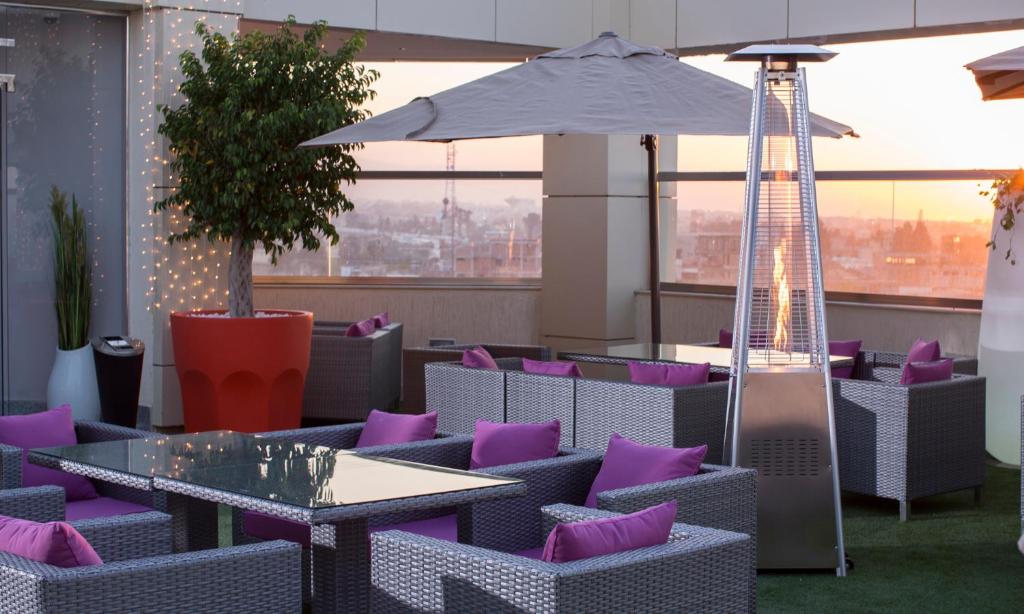 a patio with purple chairs and tables and an umbrella at ktHotels in Oulad Yaïch