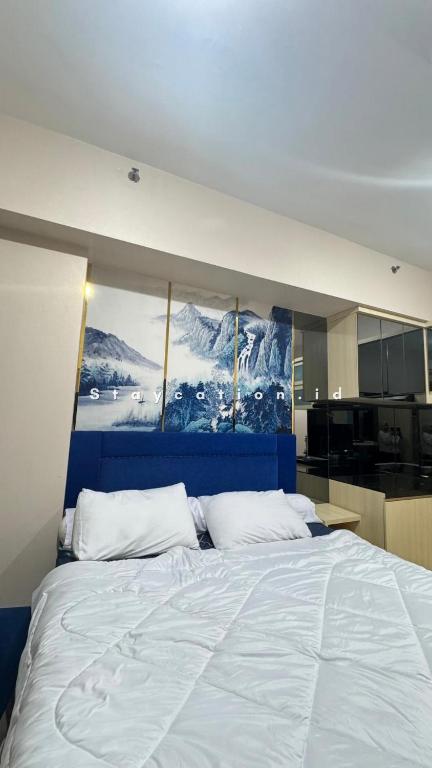a bedroom with a large bed with a painting on the wall at Apart Anderson in Surabaya