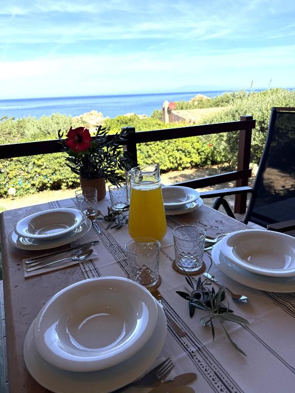 a table with plates and glasses and a bottle of orange juice at Villa Oliva in Costa Paradiso
