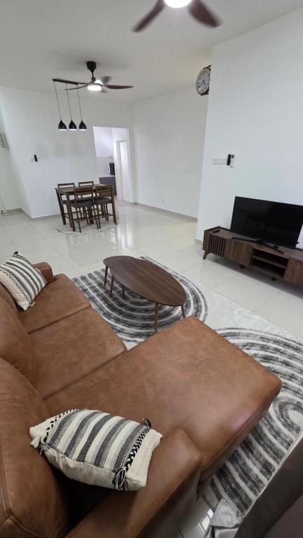 a living room with a brown couch and a table at Rizqi Homestay Sireh Residence Apartment Kota Bharu in Kota Bharu
