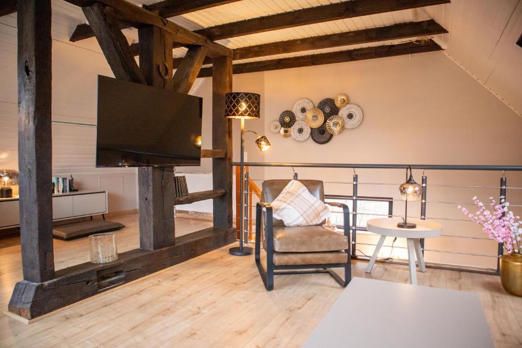 a living room with a tv and a chair and a table at Lütt Heidjer Hus in Buchholz in der Nordheide