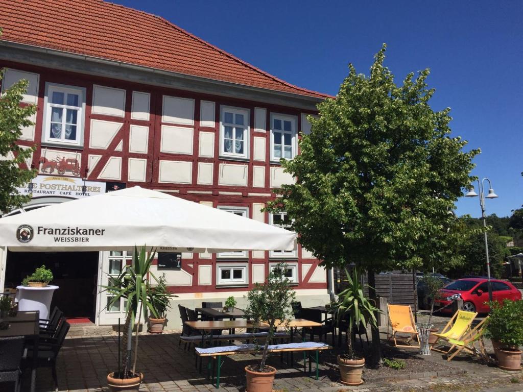 a building with tables and umbrellas in front of it at Hotel Alte Posthalterei in Creuzburg
