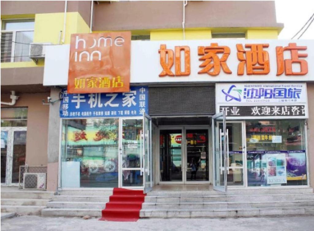 Home Inn Shenyang Shiyiwei Road Qingnian Street في شنيانغ: متجر به لافتات على جانب المبنى