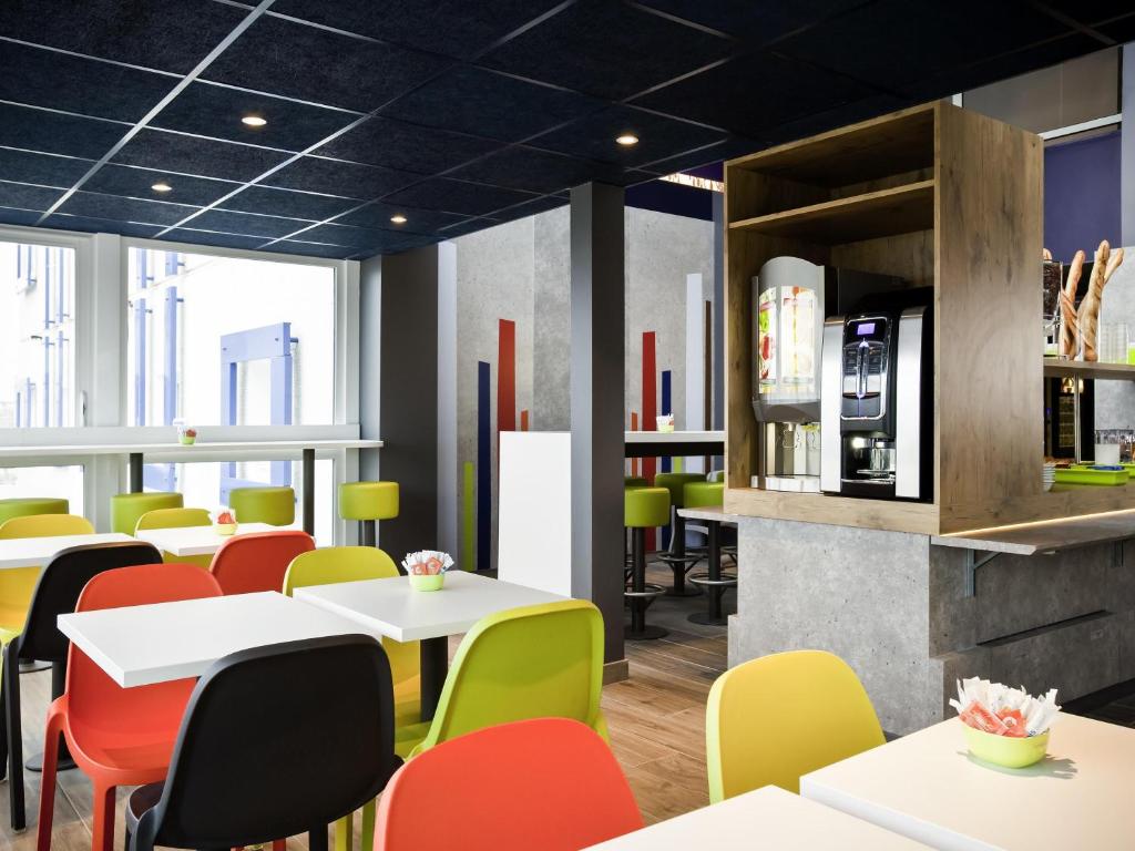 un ristorante con tavoli bianchi e sedie colorate di ibis budget Pontault Combault RN4 Marne La Vallée a Pontault-Combault