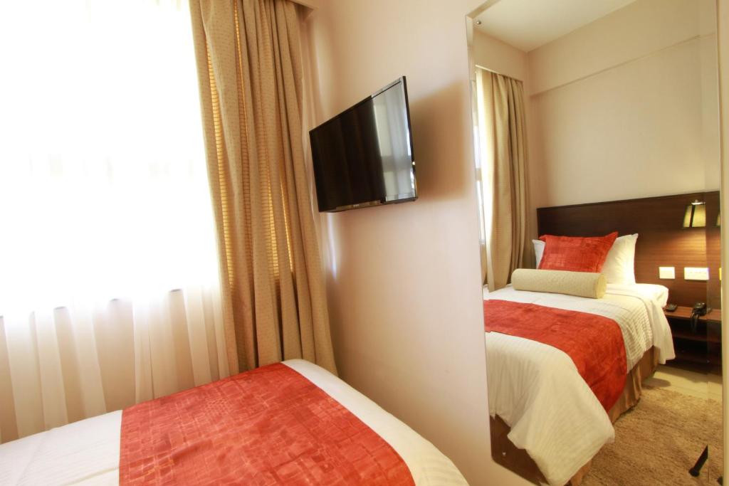 a hotel room with two beds and a flat screen tv at Hotel Rio in Nairobi