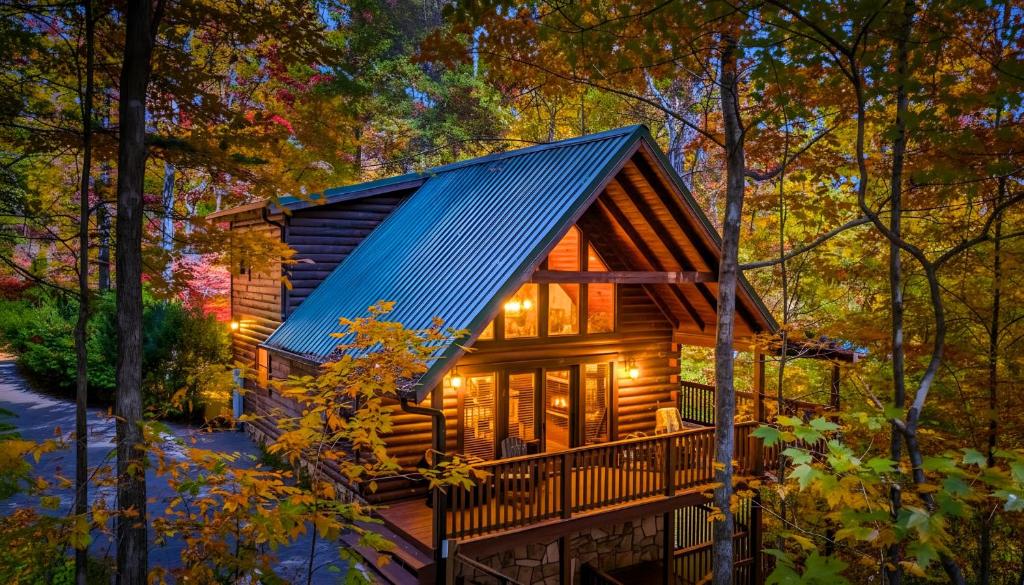 a log cabin in the woods with lights on at Gray Fox Den Theater & Arcade, Hot Tub, Views in Gatlinburg