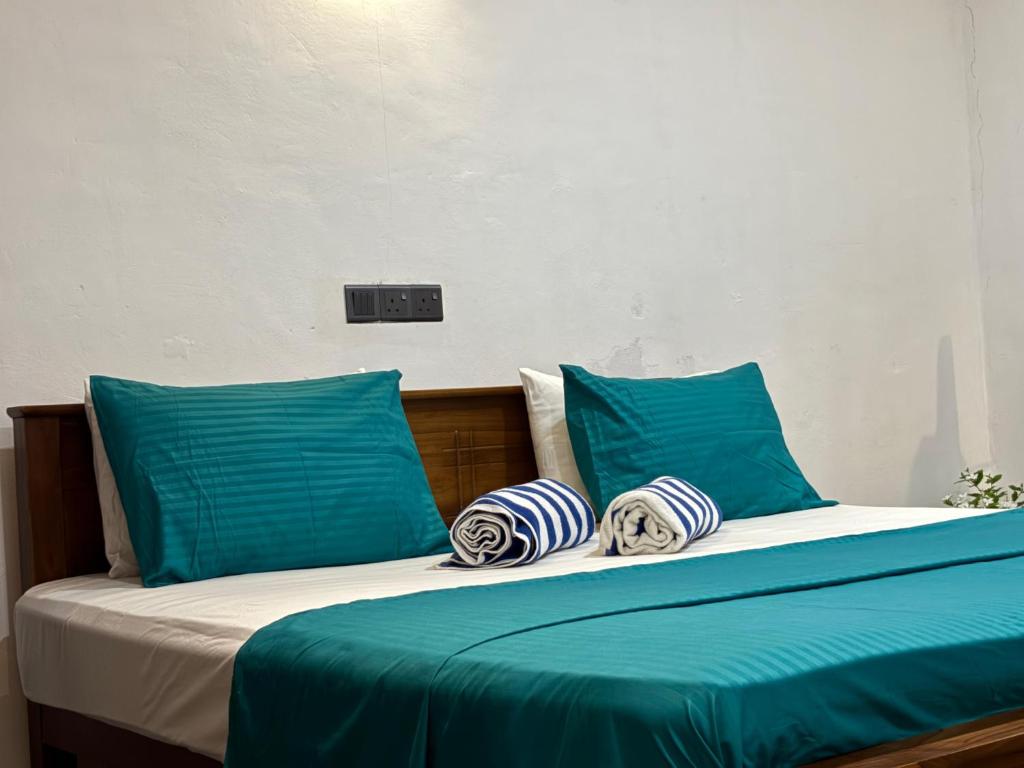 Una cama con almohadas azules y blancas. en New mahi mahi villa, en Dikwella