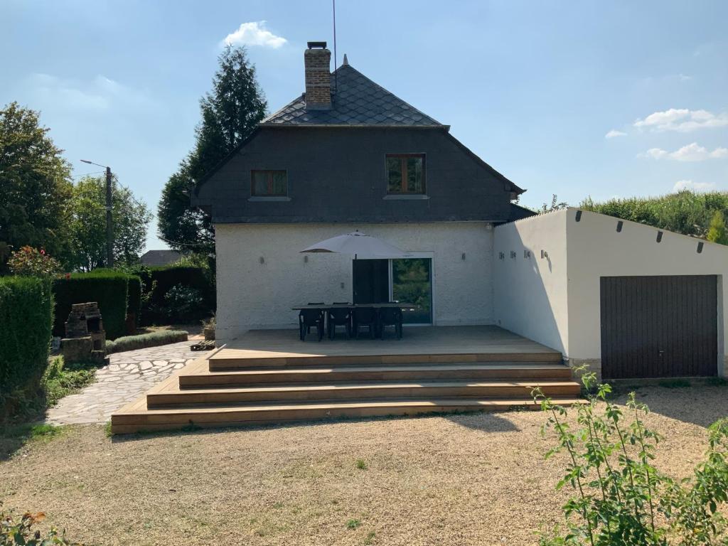 a house with a patio with a table and an umbrella at Cozy family home in Champagne-en-Ardenne 8p in Rubigny
