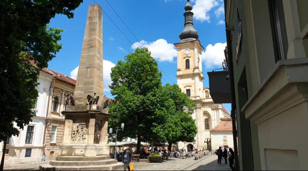 un monumento frente a un edificio con una torre de reloj en Ultra-Central Cozy Studio, Steps from Everything, en Cluj-Napoca