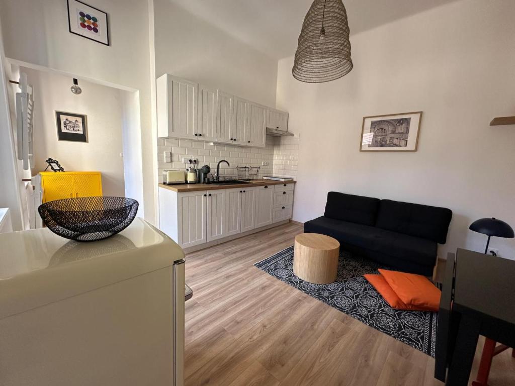 a living room with a black couch and a kitchen at Apartmán ve dvoře in Žatec