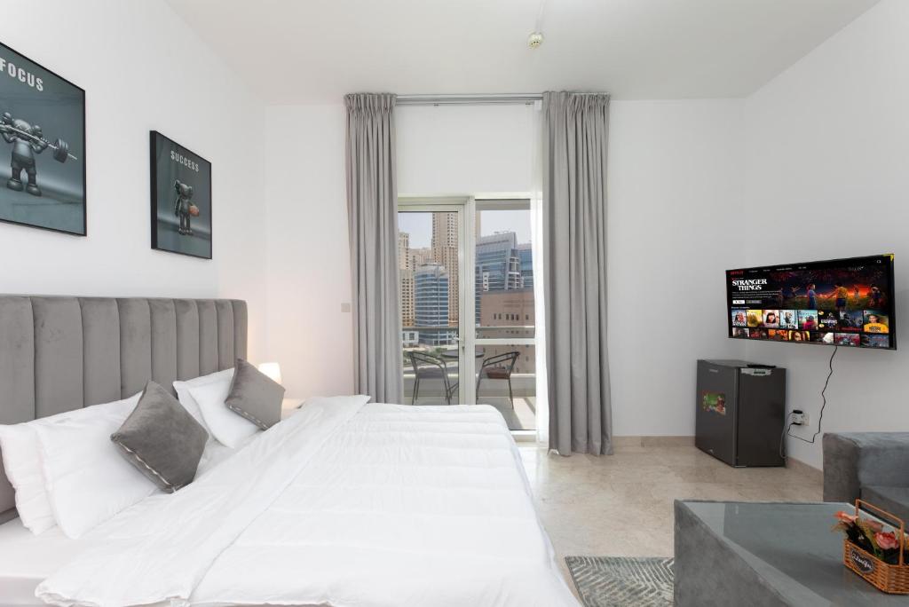a bedroom with a large white bed and a tv at Comfort Ensuite with Balcony in Dubai
