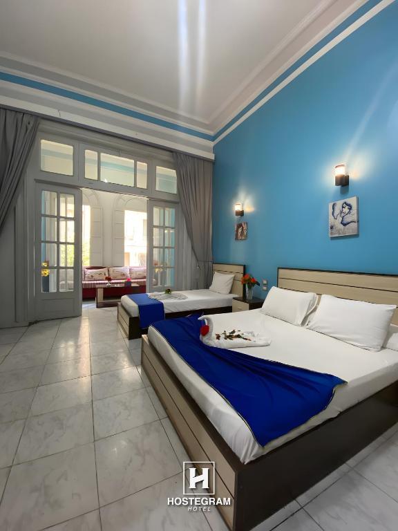 a bedroom with two beds and a blue wall at Hostgram Home - Talaat Harb Square in Cairo