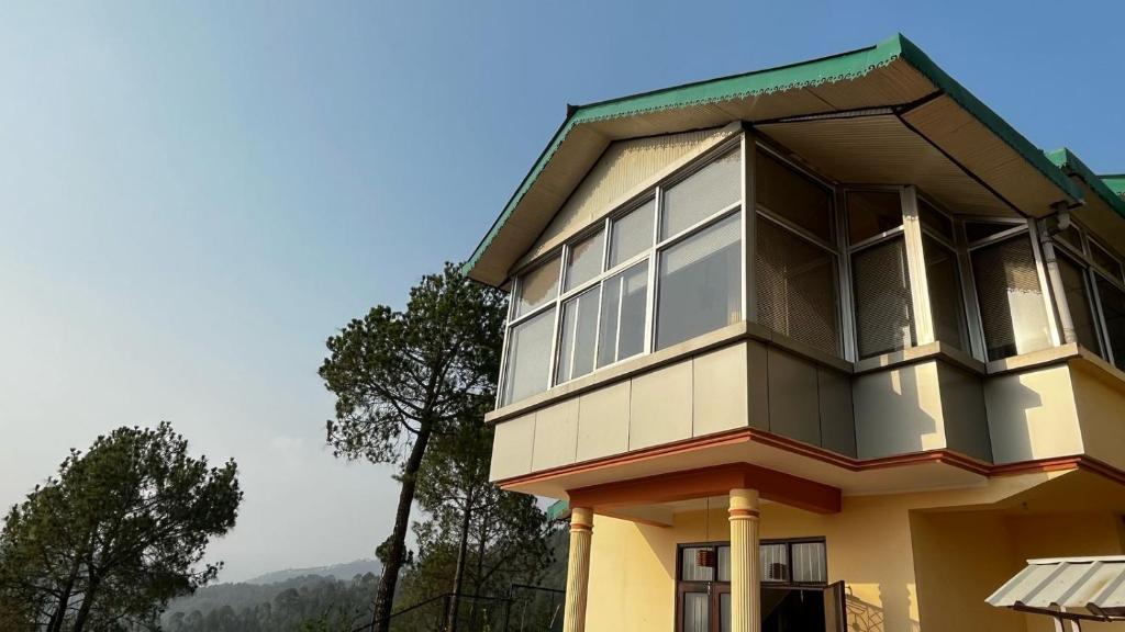 a yellow house with large windows on top of it at The Pahadi Ghar in Chail