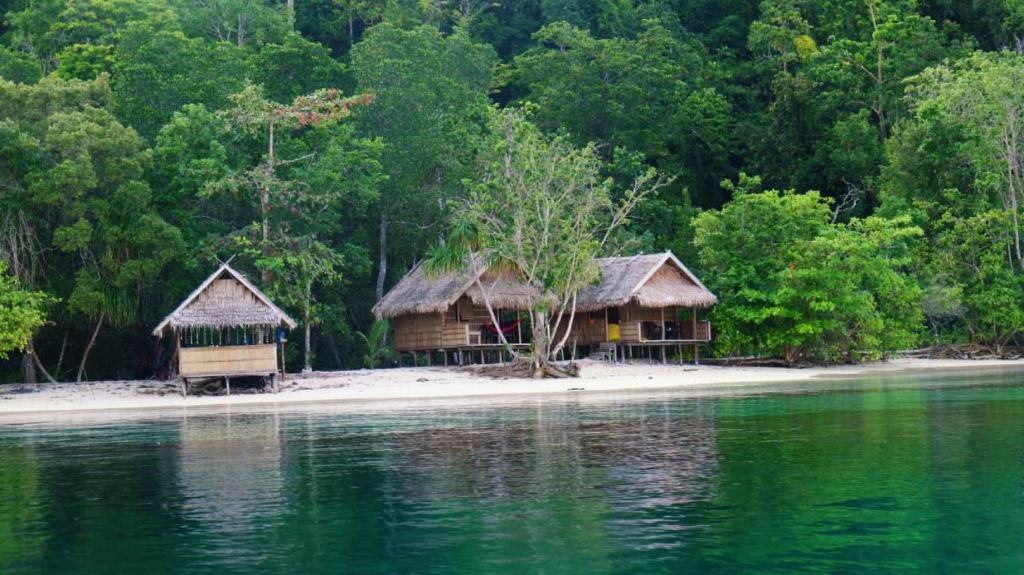 two huts on a small island in the water at Paradise Raja Ampat in Dayang
