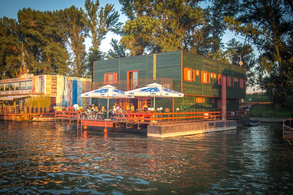 Green House Hostel في بلغراد: مطعم فيه مظلات على مرسى على نهر