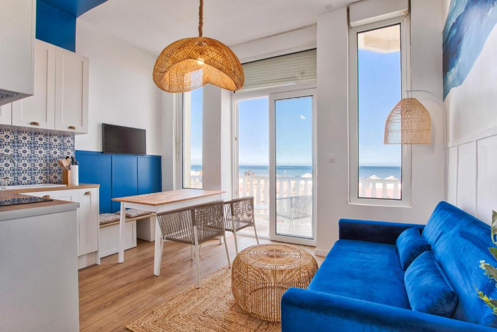 a living room with a blue couch and a table at Bleu Horizon in Villers-sur-Mer