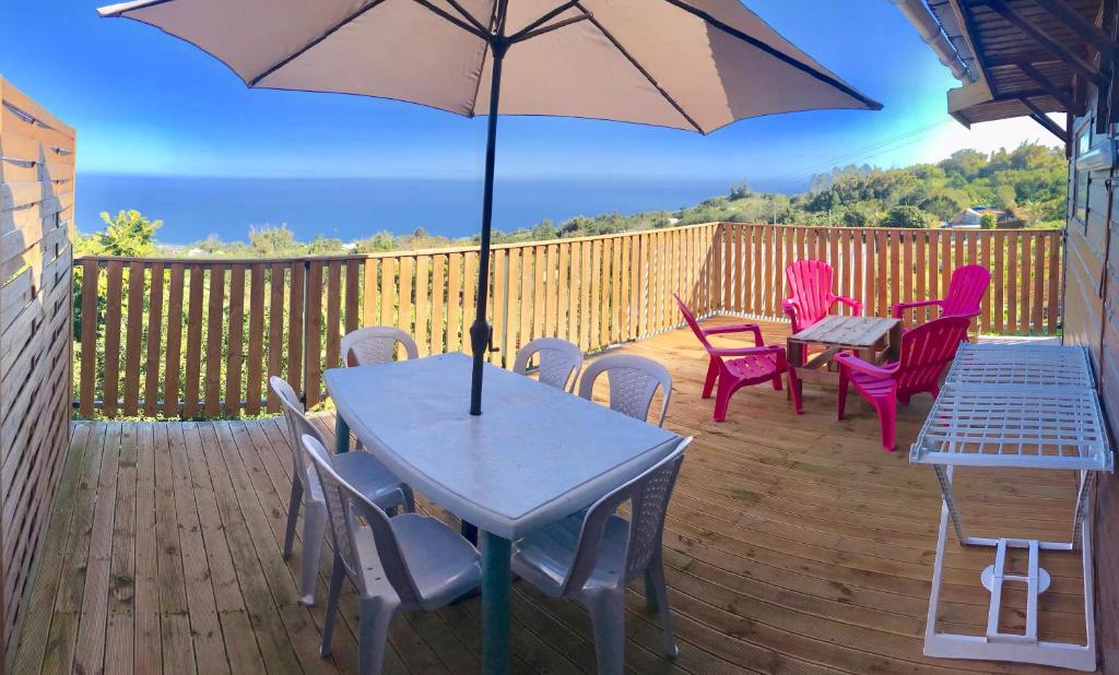 eine Terrasse mit Tischen und Stühlen und einem Sonnenschirm in der Unterkunft Au Coeur du Safran in Saint-Joseph