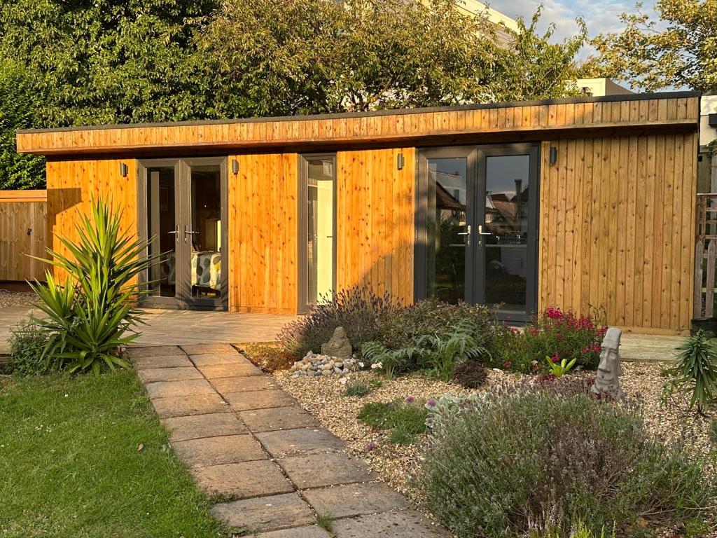 a wooden house with glass doors in a garden at Driftwood at BotanyBay - Dogs Welcome in Broadstairs