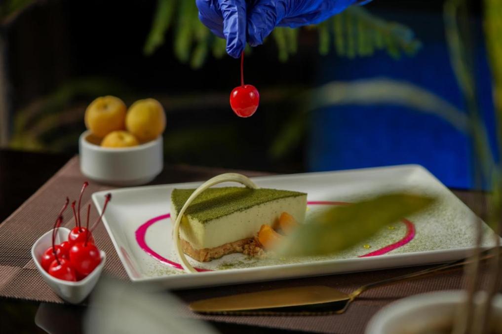 a person sprinkling a cherry on a piece of cake at Hotel Srijan in Vrindāvan