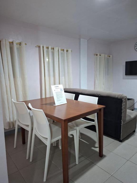 a wooden table with white chairs and a couch at Abode86 Transient-Agus in Lapu Lapu City