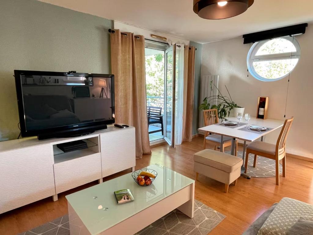 ein Wohnzimmer mit einem großen TV und einem Tisch in der Unterkunft Cosy 2P - Parking - Tram - Marché de Noël à 20min in Ostwald