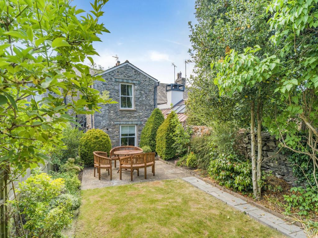 a garden with a table and chairs in front of a house at Barngarth in Cartmel