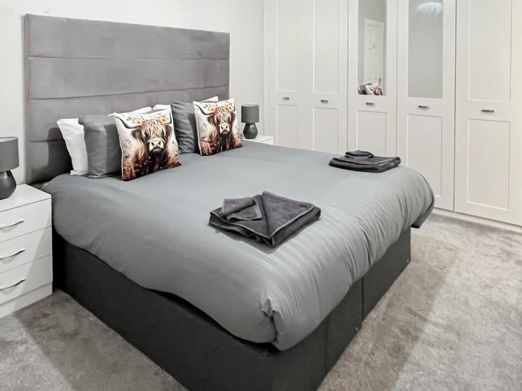 a bedroom with a large bed with a gray headboard at Cambusmoon Apartment in Gartocharn